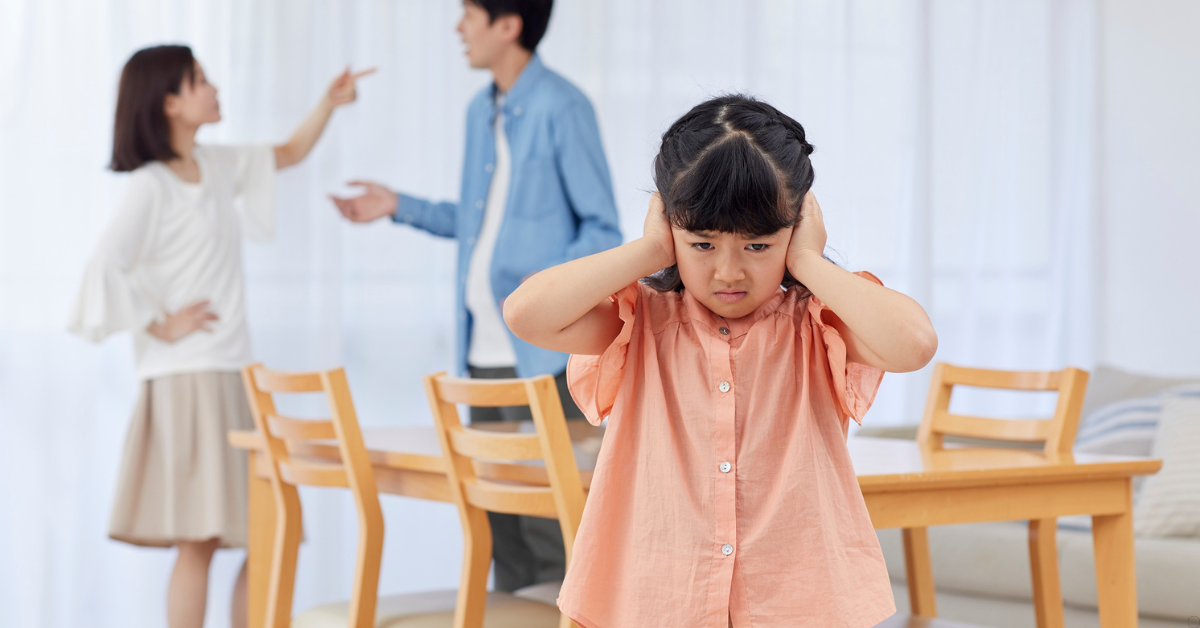Criança tapando os ouvidos enquanto os pais discutem, representando os efeitos da alienação parental