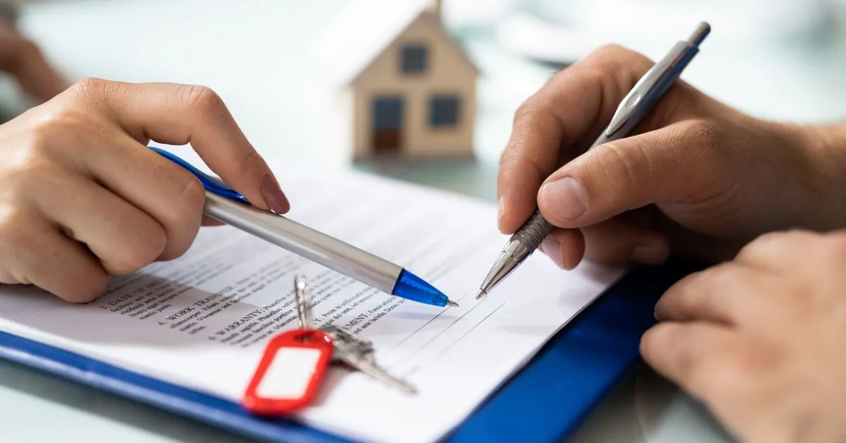 Assinatura de contrato de compra e venda de imóvel com chave e maquete de casa ao fundo