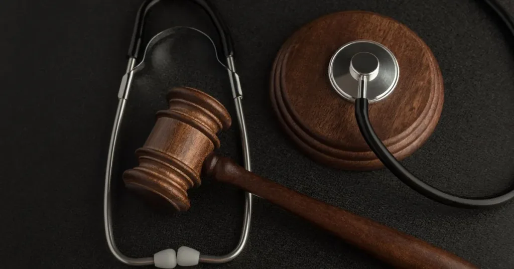 Estetoscópio e martelo da justiça sobre fundo escuro representando erro médico e complicações no tratamento