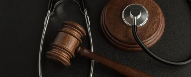 Estetoscópio e martelo da justiça sobre fundo escuro representando erro médico e complicações no tratamento