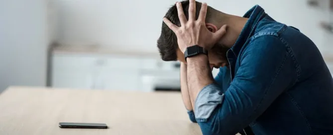 Homem sentado com as mãos na cabeça, demonstrando preocupação após ser negativado indevidamente