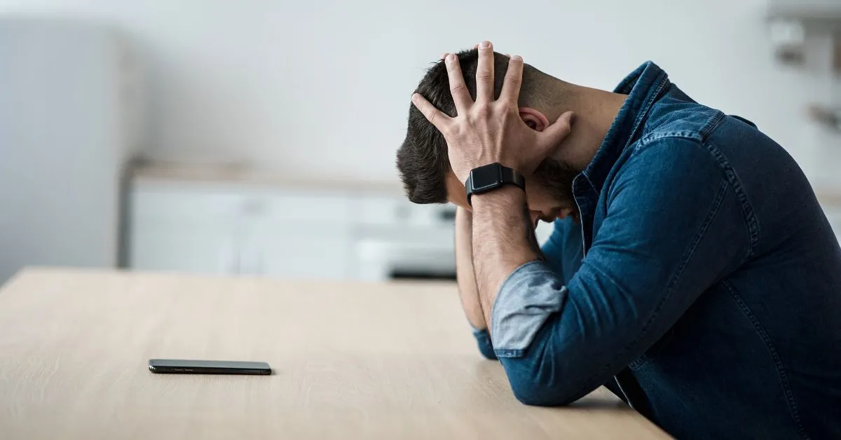 Homem sentado com as mãos na cabeça, demonstrando preocupação após ser negativado indevidamente