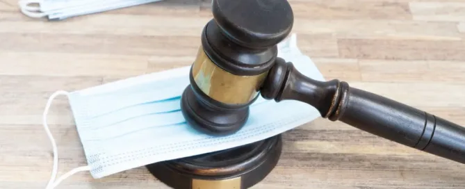 Martelo da justiça sobre máscara cirúrgica simbolizando ações judiciais contra planos de saúde