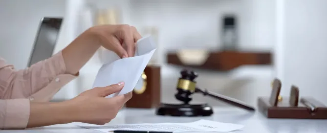 Pessoa colocando documento em envelope ao lado de martelo de juiz, representando processo de pensão alimentícia