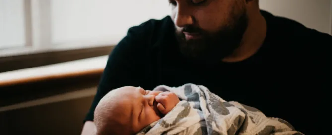 Pai segurando bebê recém-nascido no colo, representando vínculo afetivo e reconhecimento de paternidade – direito de família.