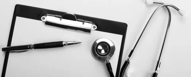 Prontuário médico com estetoscópio e caneta sobre a mesa, representando o direito à saúde e a responsabilidade por recusa de atendimento médico.