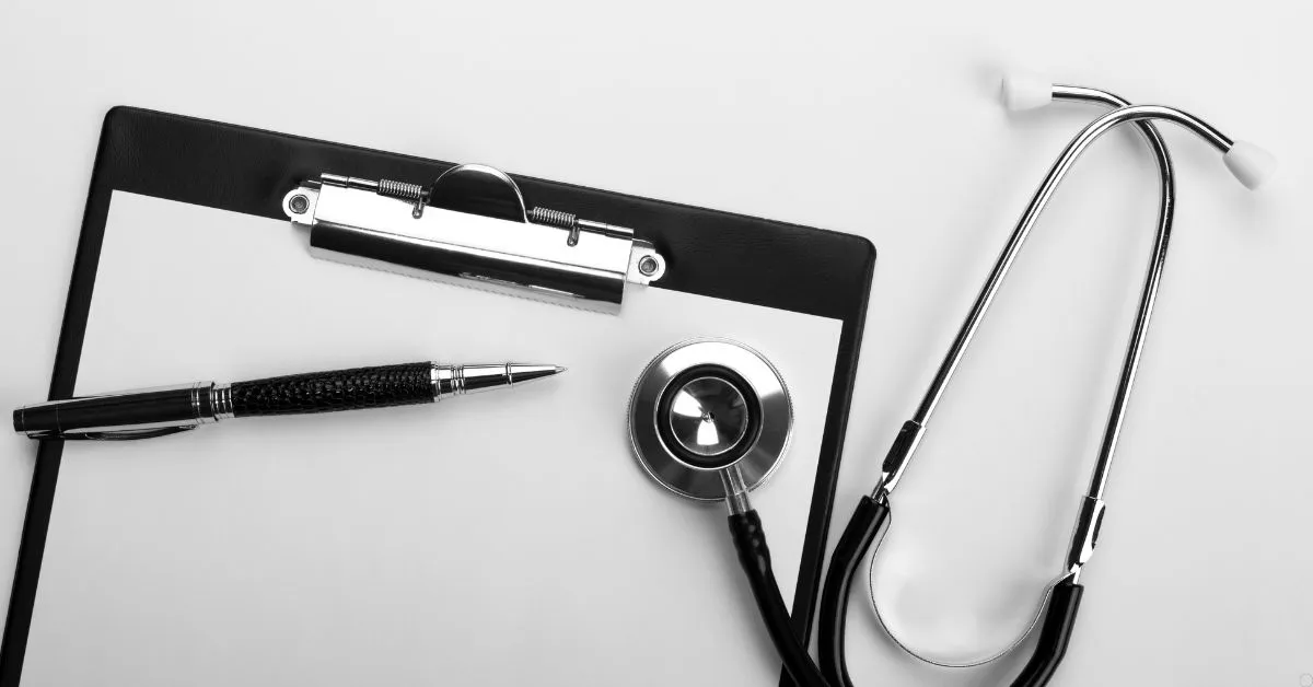 Prontuário médico com estetoscópio e caneta sobre a mesa, representando o direito à saúde e a responsabilidade por recusa de atendimento médico.