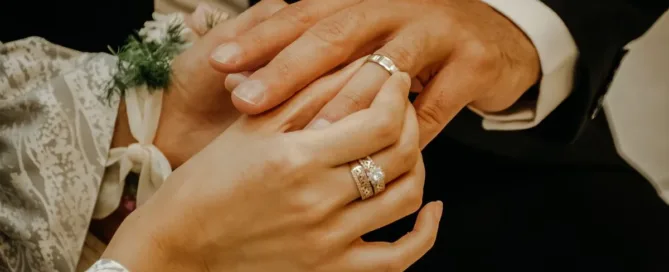 Mãos de casal com alianças simbolizando casamento e regime de bens