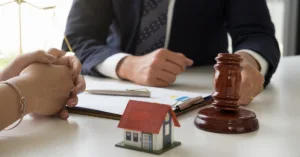 Reunião com advogado sobre regularização de imóvel com maquete de casa e martelo da justiça na mesa