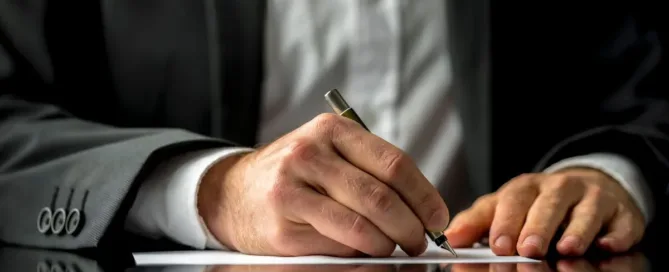Pessoa de terno assinando documento sobre testamento, herança ou legado