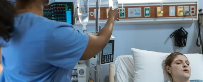 Profissional da saúde ajustando soro em paciente internada em hospital