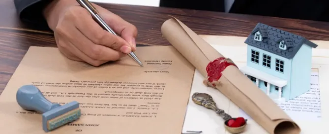 Pessoa assinando testamento com miniatura de casa ao lado, representando herança e obrigações financeiras