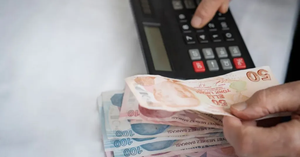 Pessoa contando dinheiro ao lado de calculadora, representando cálculo de pensão alimentícia entre ex-cônjuges