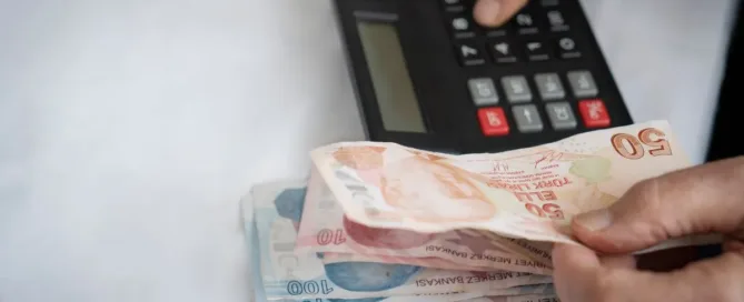 Pessoa contando dinheiro ao lado de calculadora, representando cálculo de pensão alimentícia entre ex-cônjuges