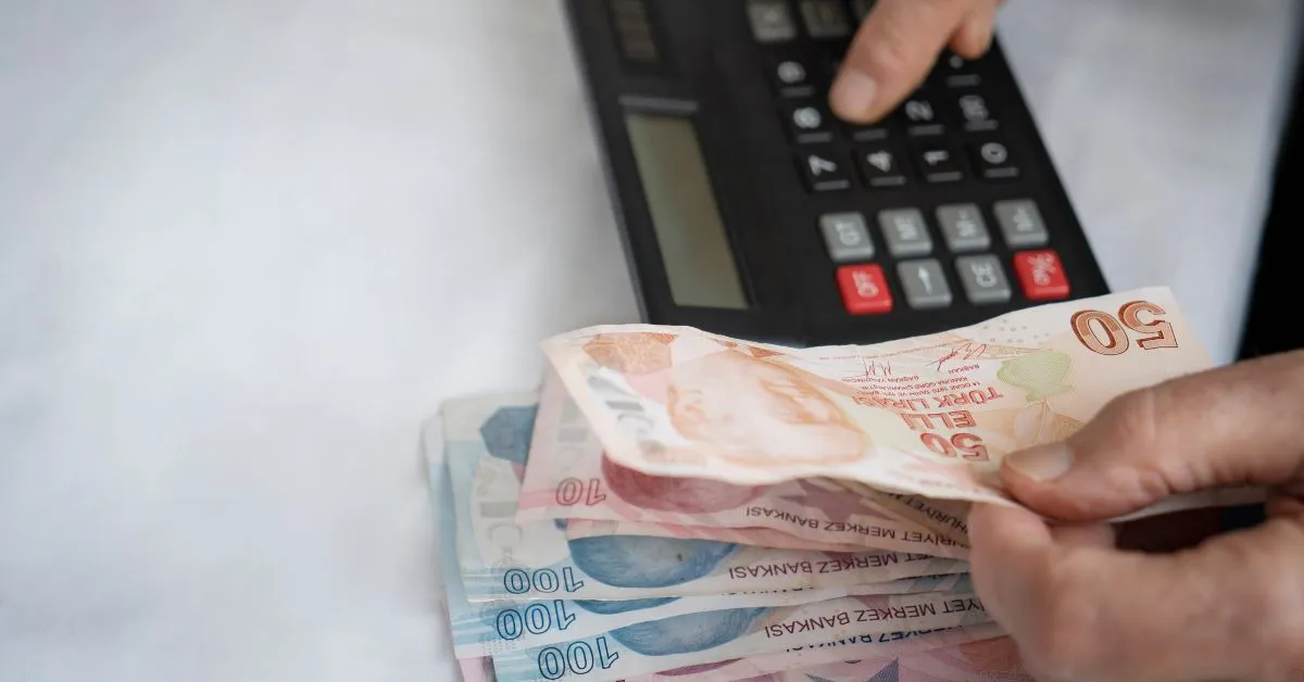 Pessoa contando dinheiro ao lado de calculadora, representando cálculo de pensão alimentícia entre ex-cônjuges