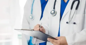 Médicos com estetoscópio analisando prontuário em prancheta hospitalar