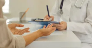 Paciente conversa com médico durante consulta para revisar alta médica precoce.