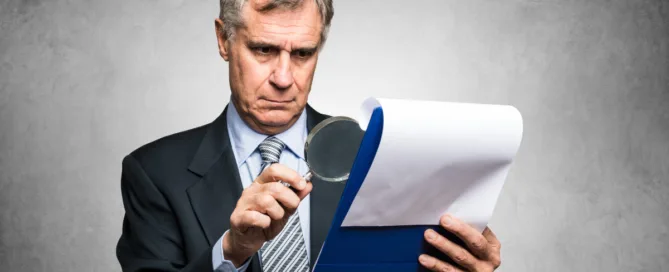 Homem analisando contrato com lupa — cláusulas contratuais na compra de imóvel