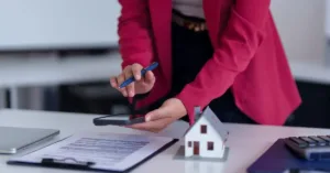 Profissional analisando contrato de compra e venda de imóvel sobre mesa de escritório.