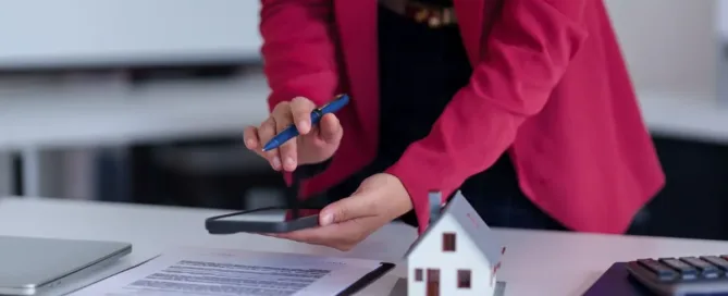 Profissional analisando contrato de compra e venda de imóvel sobre mesa de escritório.