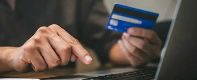 Pessoa segurando cartão de crédito e digitando no notebook para cancelar compra online