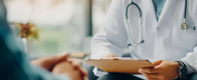 Médico segurando prontuário durante consulta com paciente, ilustrando recusa de hospital em fornecer atestado ou laudo médico