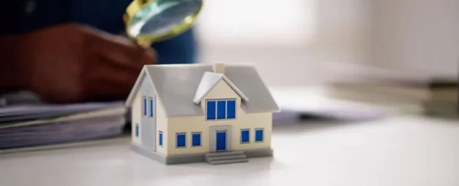 Casa em miniatura sob análise com lupa, representando venda de imóvel em inventário