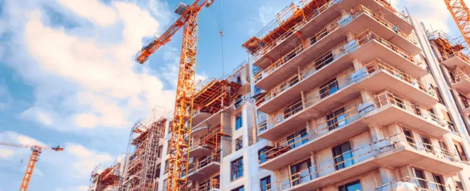 Prédio em construção com guindastes, ilustrando atraso na entrega do imóvel.