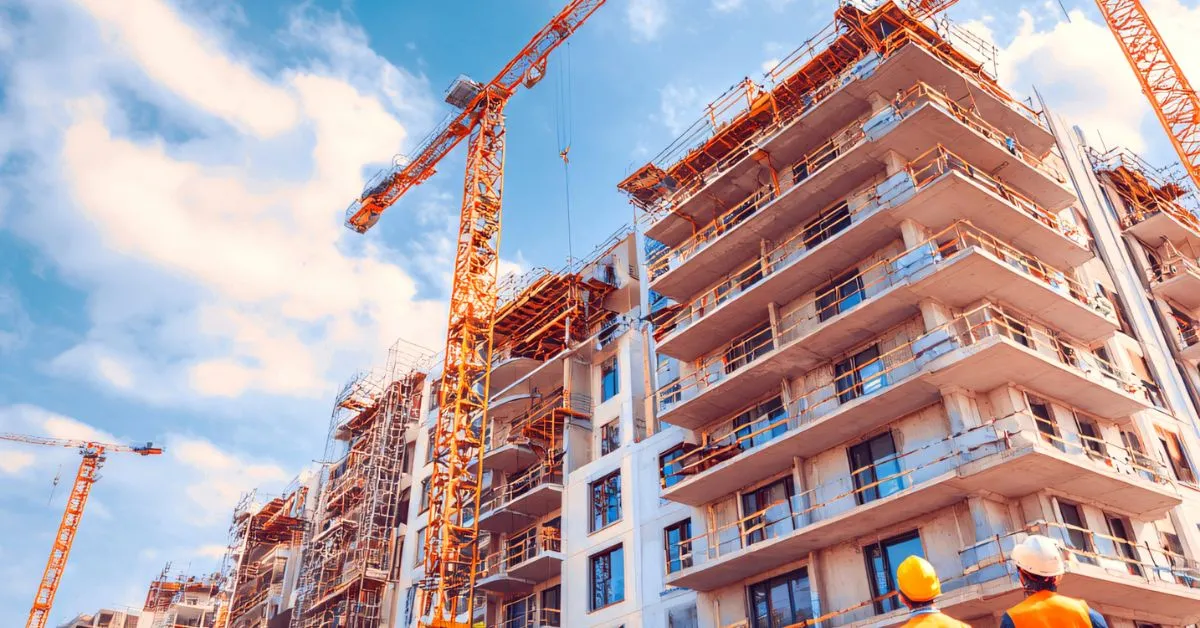 Prédio em construção com guindastes, ilustrando atraso na entrega do imóvel.