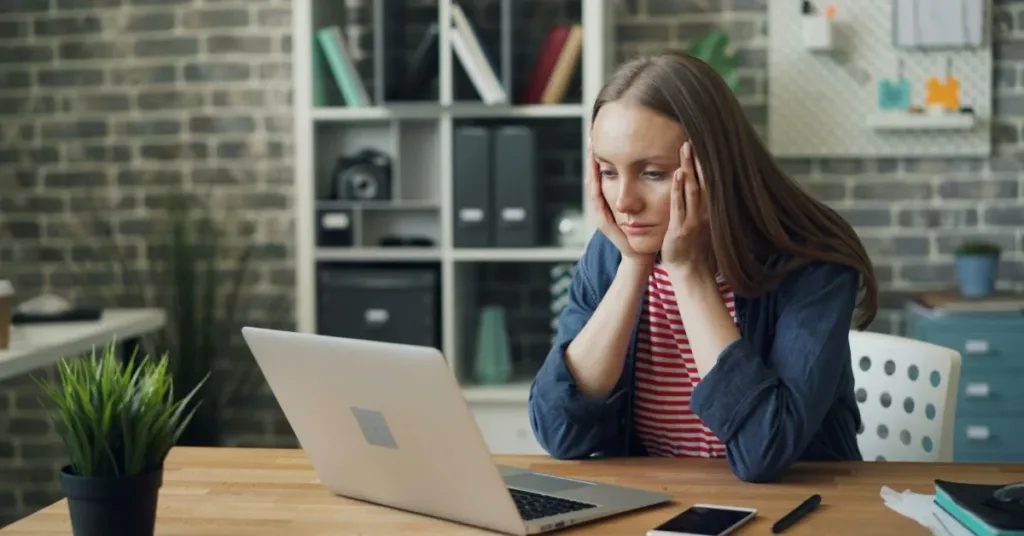 Mulher preocupada usando o computador, representando vítima de fraude com dados pessoais.