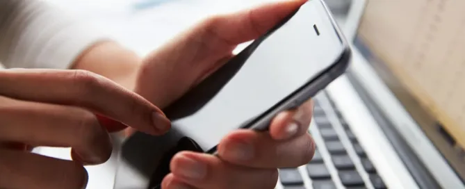 Pessoa segurando celular próximo ao notebook, simbolizando gravação de conversa como prova judicial.