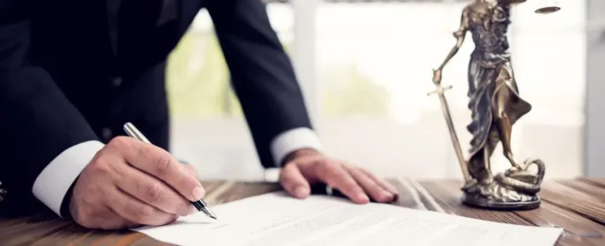 homem assinando documento jurídico ao lado de estátua da justiça, representando testamento particular ou público