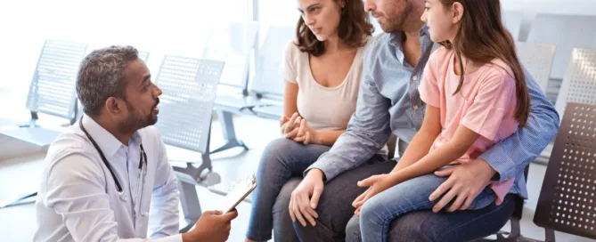Pais separados conversando com médico sobre decisões médicas do filho em ambiente hospitalar.