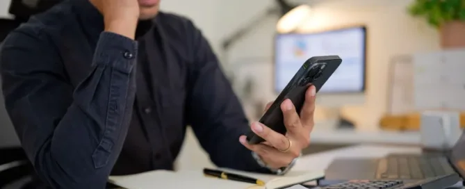 Homem analisando celular com expressão de preocupação após possível bloqueio de conta bancária sem aviso prévio.