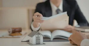 Análise jurídica de benfeitorias em imóvel alugado, com contrato de locação e maquete de casa sobre a mesa.