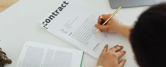 Pessoa assinando contrato em papel, analisando cláusulas antes da assinatura, em situação que pode indicar contrato assinado sob engano.