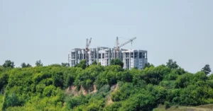 Construção de edifício em área de preservação permanente, ilustrando imóvel localizado em APP e os limites legais para regularização ambiental.