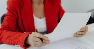 Pessoa analisando e assinando documento de renúncia de herança, representando decisão consciente no direito de sucessões.