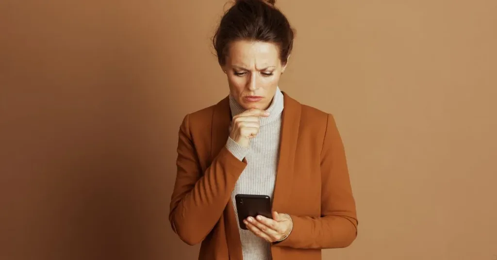 Consumidora preocupada olhando o celular após cobrança indevida depois do cancelamento de serviço