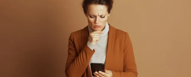 Consumidora preocupada olhando o celular após cobrança indevida depois do cancelamento de serviço