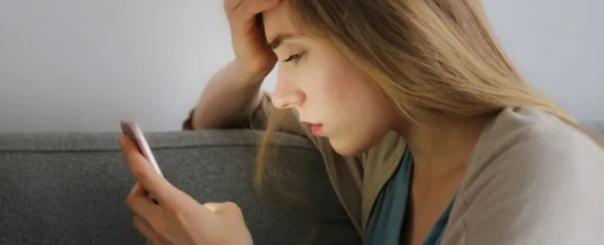 Mulher preocupada olhando o celular após erro em transferência bancária ou Pix por engano