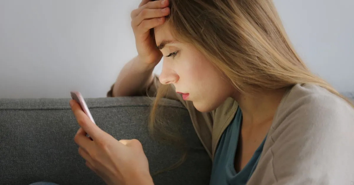 Mulher preocupada olhando o celular após erro em transferência bancária ou Pix por engano