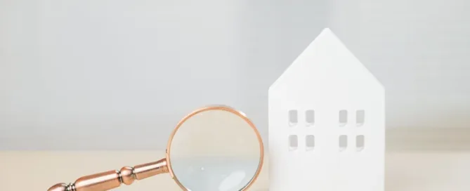 Casa em miniatura com lupa representando análise de contrato de compra e venda de imóvel que pode ser anulado
