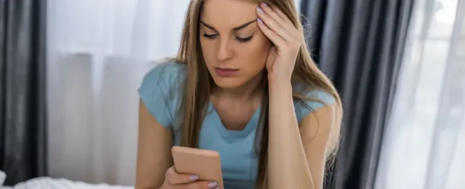 Mulher preocupada olhando o celular após atendimento abusivo ao cliente por empresa