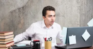 Homem surpreso diante de notebook após conta bloqueada em plataforma digital