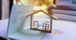 Casa em miniatura sobre documentos representando imóvel com inventário em andamento e negociação imobiliária