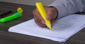 Pessoa destacando informações em documentos de cobrança extrajudicial para empresas