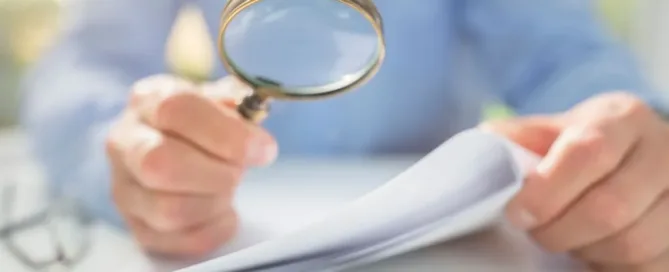 Pessoa analisando contrato com lupa para verificar cláusula de fidelidade e multa por cancelamento.
