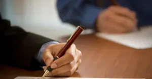 Pessoa assinando contrato social de empresa sobre uma mesa