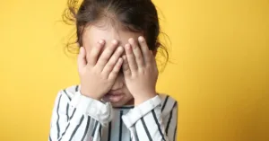 Criança com as mãos sobre o rosto, representando abandono afetivo e os impactos da ausência parental.